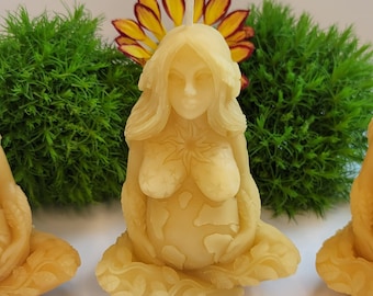 May include: A hand-crafted beeswax candle in the shape of a pregnant woman with a flower crown. The candle is detailed with a floral design and a depiction of the earth on the woman's belly.