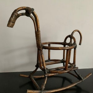 May include: A brown wicker rocking chair shaped like a horse. The chair has a rounded back and a seat with a woven pattern. The rocking base is made of thick wicker.