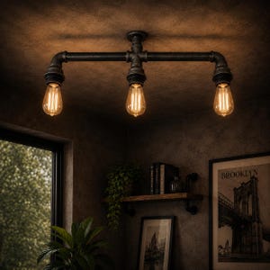 Puede incluir: Lámpara de techo de estilo industrial con tres bombillas Edison expuestas. La lámpara está hecha de tuberías y accesorios de metal negro, creando una estética vintage. Las bombillas emiten una luz cálida y acogedora, perfecta para un loft o espacio moderno.