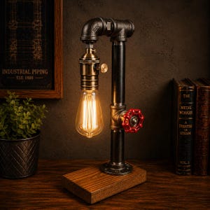 May include: Industrial-style desk lamp made from black metal pipes, featuring a vintage Edison bulb and a red valve handle. The lamp sits on a wooden base and has a warm, inviting glow. The lamp is approximately 12 inches tall.