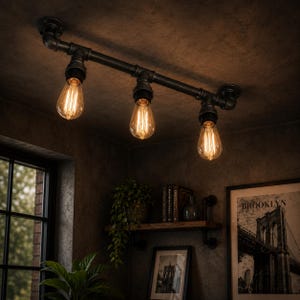 May include: A black metal industrial ceiling light with three exposed Edison-style bulbs. The light is made from pipes and fittings, mounted on a dark ceiling. The warm light from the bulbs contrasts with the cool tones of the room.