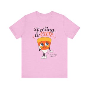 May include: A light pink short-sleeve t-shirt featuring a cartoon candy corn character with a face, arms, and legs. The text above reads Feeling a-CUTE, and text below the character reads Acute angle (<90°). The design uses orange, yellow, and white.