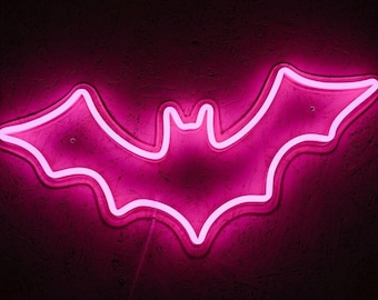 May include: A pink neon sign shaped like a bat. The sign is lit up and glowing against a dark background.