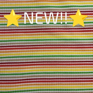 May include: A striped fabric with alternating bands of red, orange, yellow, green, brown, and white. The fabric has a ribbed texture. The words "NEW!!" are printed in white on the fabric.