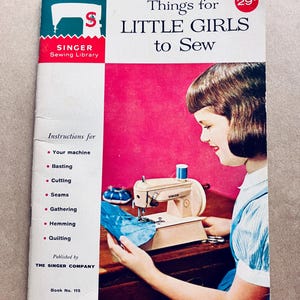 May include: A vintage Singer sewing book, "Things for Little Girls to Sew", showing a girl using a Singer sewing machine. The cover is white and red, with instructions for sewing techniques such as basting, cutting, and quilting.