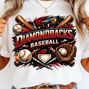 May include: White t-shirt featuring a baseball-themed graphic. The design includes baseball bats, baseballs, a glove, and the words "Diamondbacks Baseball" in red and black. The graphic has a snake eye.