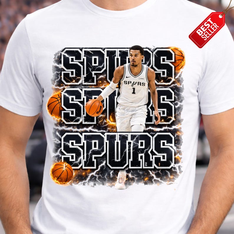 Pu&ograve; includere: T-shirt bianca con un giocatore di basket in uniforme Spurs, con la parola "SPURS" in grassetto e contornata. Il design include palloni da basket e un'etichetta "Best Seller".