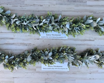 Może przedstawiać: Dwa wieńce z eukaliptusa i owczych uszu. Górny wieniec jest oznaczony jako "Extra Thickness: Lamb's Ear with Extra Eucalyptus (D)". Dolny wieniec jest oznaczony jako "Extra Thickness: Extra Lamb's Ear with Eucalyptus (E)".