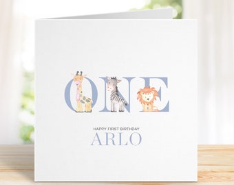 Op de afbeelding: Een witte kaart met blauwe letters die "ONE" spellen met een giraffe, zebra en leeuw in elke letter. De tekst "HAPPY FIRST BIRTHDAY ARLO" staat onder de letters.