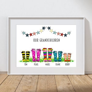 May include: A white framed print with a colorful illustration of a string of stars and five pairs of rain boots with names underneath: Tom, Pearl, Mabel, Frank, and Bobby. The text "Our Grandchildren" is above the boots.