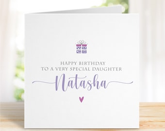 Puede incluir: Una tarjeta blanca con una ilustración de caja de regalo morada y el texto "Feliz cumpleaños a una hija muy especial Natasha" con un pequeño corazón morado.