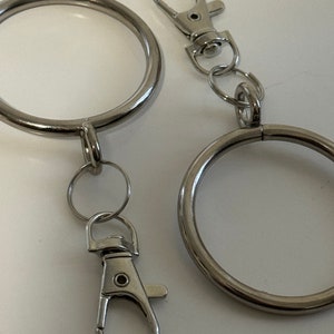 Puede incluir: Dos llaveros plateados con un anillo grande y un anillo m&aacute;s peque&ntilde;o con un cierre de langosta.