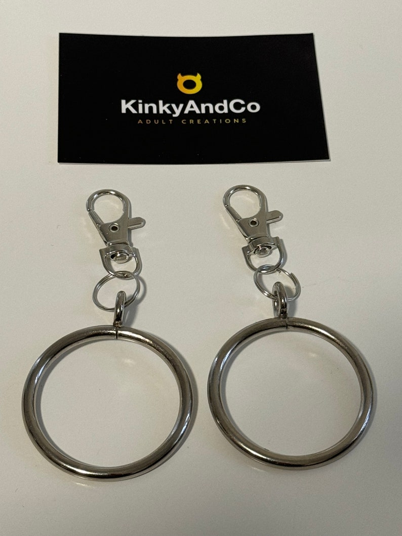 Puede incluir: Dos anillos de metal plateado con un clip de metal plateado unido a cada anillo. Los anillos tienen un di&aacute;metro de aproximadamente 5 cm.