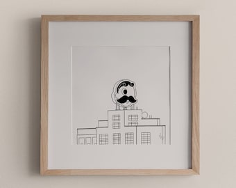 Puede incluir: Un dibujo lineal en blanco y negro enmarcado de un edificio con un gráfico de bigote estilizado en la parte superior. La obra de arte está en un marco de madera clara y cuelga de una pared de color neutro. Un jarrón decorativo y un pequeño recipiente redondo están en primer plano.