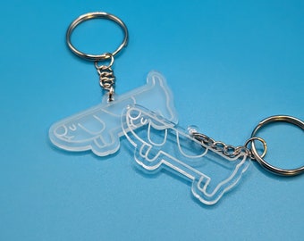 Peut inclure: Deux porte-clés en acrylique transparent en forme de chien. Les porte-clés sont attachés à des anneaux de clés argentés.