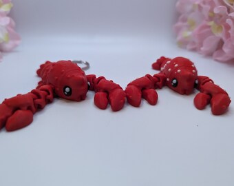Peut inclure: Deux breloques de homard rouge avec des détails blancs. Un homard a des points blancs et l'autre a des yeux blancs.
