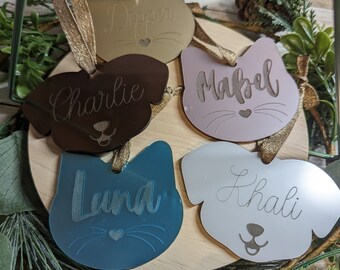 Peut inclure: Cinq décorations de Noël personnalisées pour animaux de compagnie, chacune avec une silhouette d'animal différente et un nom. Les décorations sont en acrylique et ont une finition miroir. Les noms sont "Dipper", "Charlie", "Mabel", "Luna" et "Khali".