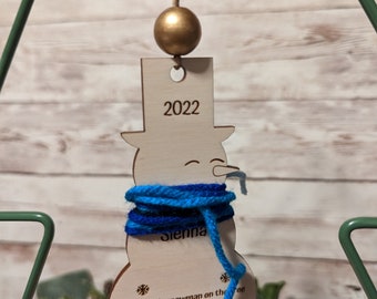 Peut inclure: Une décoration de Noël en bois en forme de bonhomme de neige avec une écharpe en laine bleue, l'année 2022 et le nom Sienna. La décoration a un poème sur le bonhomme de neige qui grandit chaque année.