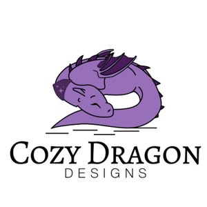 May include: Purple cartoon dragon curled up sleeping with a star on its head. The text "Cozy Dragon Designs" is below the dragon.
