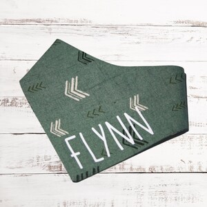 May include: Green bandana with a white arrow pattern and the name "FLYNN" written in white.