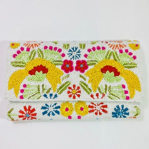 Pu&ograve; includere: Una pochette bianca con perline e un design floreale colorato. I fiori sono gialli, rossi, rosa, arancioni, verdi e blu.
