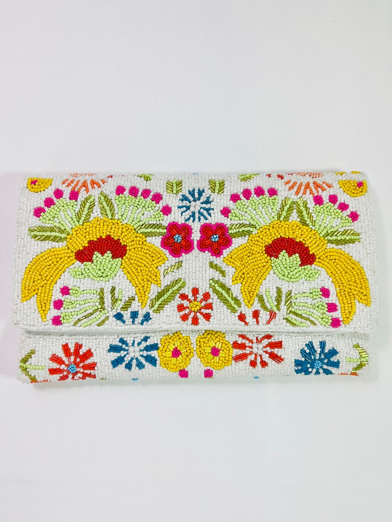 Pu&ograve; includere: Una pochette bianca con perline e un design floreale colorato. I fiori sono gialli, rossi, rosa, arancioni, verdi e blu.