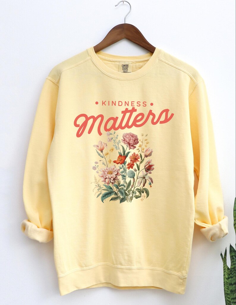 May include: Yellow sweatshirt with a floral design and the text "KINDNESS MATTERS" in red.