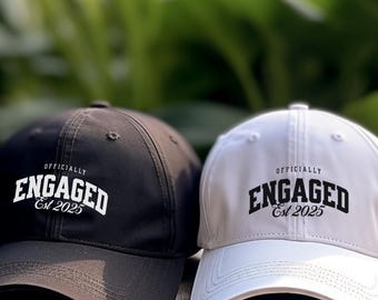 May include: Two black and white baseball caps with the text "Officially Engaged Est 2025" on the front.