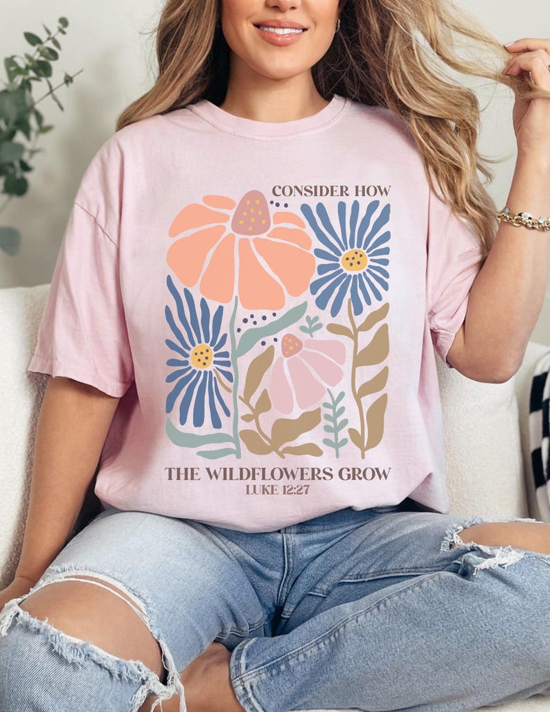 May include: A pink t-shirt with a floral design and the text "Consider how the wildflowers grow, Luke 12:27".