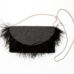 May include: A black beaded clutch with a feather trim and a silver chain strap.