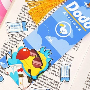 May include: A blue and yellow bookmark featuring a cartoon dodo bird wearing sunglasses and a pilot's hat. The bookmark has the text "Dodo Airlines" and a ticket with the text "Dodoair Love at First Flight".
