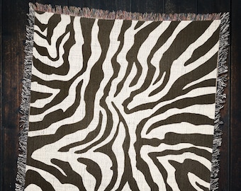 Könnte beinhalten: Eine gewebte Wolldecke mit Zebra-Muster in Schwarz und Weiß. Die Decke hat einen Fransenrand.