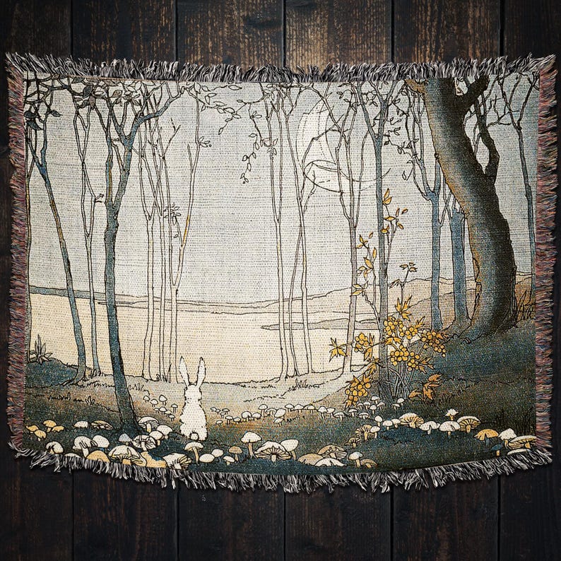 May include: A woven tapestry featuring a white rabbit standing in a forest with a moon in the background. The forest is depicted with tall, thin trees and a river in the distance. The tapestry has a fringed border.