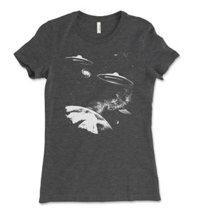 May include: A dark gray t-shirt with a white graphic of a planet and multiple flying saucers in a starry sky.