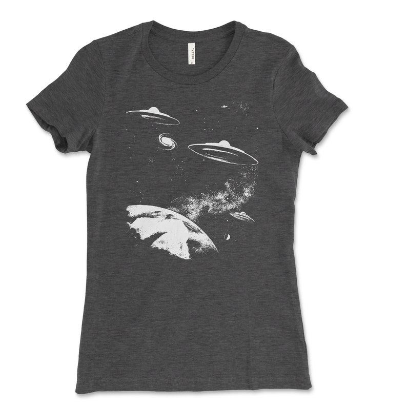 May include: A dark gray t-shirt with a white graphic of a planet and multiple flying saucers in a starry sky.