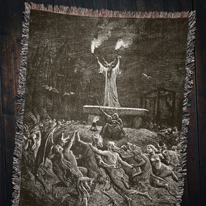 May include: A black and white tapestry depicting a scene from a classic horror story. A horned figure stands on a platform, raising their arms in the air. Below, a group of figures with horns and tails are gathered around the platform.