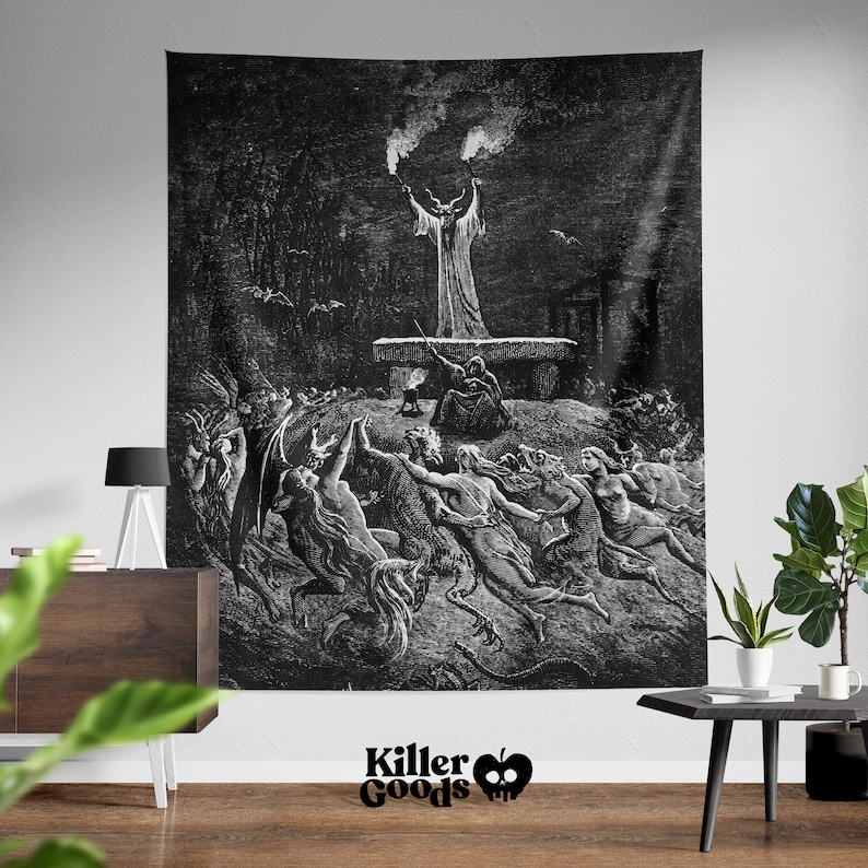 May include: Black and white tapestry featuring a vintage illustration of a devilish figure with horns and a long robe, surrounded by other figures in a dark forest setting. The tapestry has a black background and the figures are depicted in a detailed, intricate style.