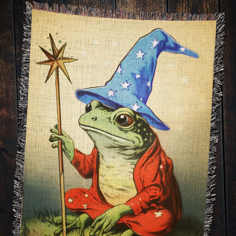 Op de afbeelding: Een groene kikker met een blauwe en witte sterren-gepatroneerde tovenaarshoed en een rode mantel houdt een houten toverstaf met een ster erop vast. De kikker zit op een bruine en groene achtergrond.