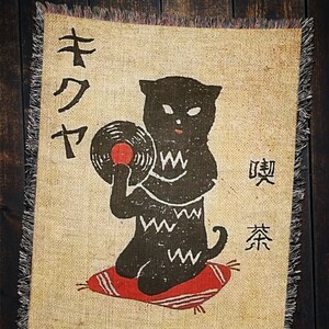 May include: A black cat with a record player and the Japanese text "キクヤ" and "喫茶" on a tan background.