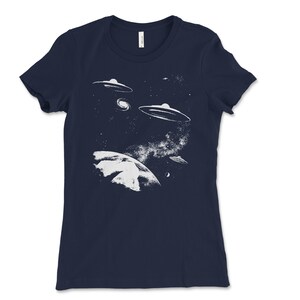 May include: A navy blue t-shirt with a white graphic of a planet and three flying saucers in a starry sky.