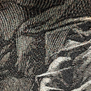 May include: Close-up of a black and white woven fabric with a textured pattern. The fabric has a subtle sheen and a slightly irregular surface.