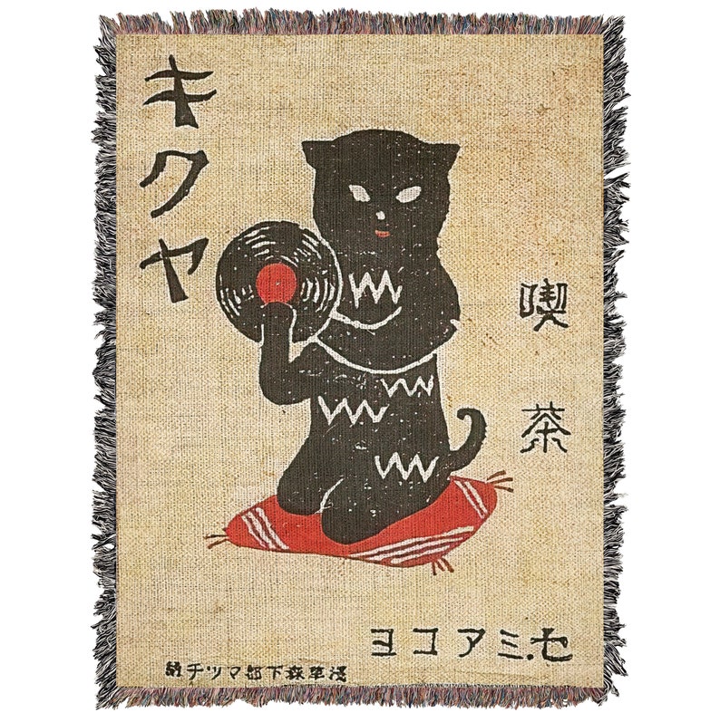May include: A black cat holding a vinyl record with a red label, sitting on a red cushion. The cat is wearing a black and white patterned shirt. The background is a beige woven fabric with Japanese text that reads "キクヤ" and "喫茶".