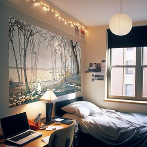 May include: A bedroom with a white bed, a desk with a laptop, and a large tapestry on the wall depicting a forest scene with a white rabbit. The tapestry is a light blue and gray color with a light pink sky. The room has a white ceiling with string lights and a white lampshade hanging from the ceiling.