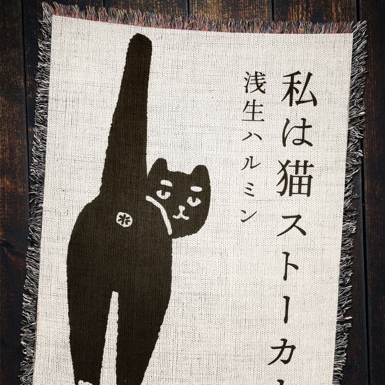 May include: A black cat with its tail raised high in the air, looking over its shoulder. The cat is on a cream-colored background with the text "I am a cat,  a stray" in Japanese.