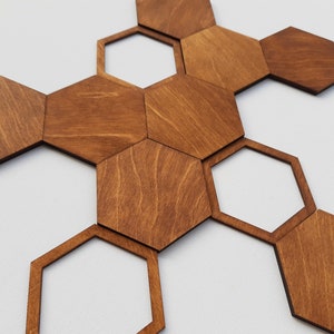 Conjunto de 11 peças hexagonais geométricas para decoração de parede em madeira, estilo moderno com padrão de favo de mel e acabamento em nogueira.