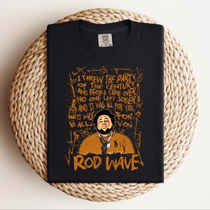 K&ouml;nnte beinhalten: Schwarzes T-Shirt mit einer Grafik von Rod Wave und dem Text: "Ich habe die Party des Jahrhunderts geschmissen und die Leute kamen...und es war alles f&uuml;r dich." Das Design ist braun und orange.