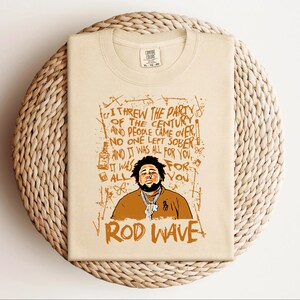 K&ouml;nnte beinhalten: Beiges T-Shirt mit einer Grafik von Rod Wave und dem Text "I threw the party of the century and people came over. No one left sober and it was all for you." Der Text "Rod Wave" steht unten.