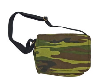 May include: A camouflage-patterned shoulder bag with a black adjustable strap. The bag has a flap closure and a small pocket on the front.