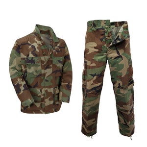 May include: Camouflage military uniform set, featuring a jacket and pants in a woodland pattern. The jacket has a button-up front and multiple pockets. The pants have a straight leg and cargo pockets.