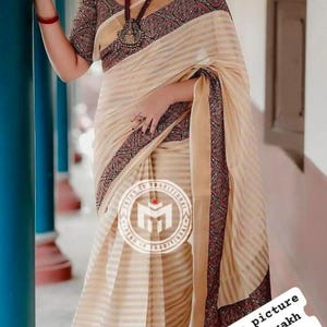 May include: Cream-coloured saree with striped pattern and patterned border. The blouse has a matching patterned design. The image includes the text "Reference picture only for ajrakh patching pattern".